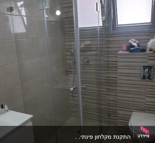 מקלחון זכוכית עם ראש מקלחת וקירות אריחים